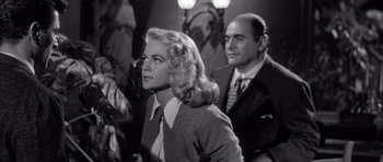 Movie still from “The Tarnished Angels” (1957), directed by Douglas Sirk – A man and a woman sitting next to each other in a room; Medium shot, Low angle