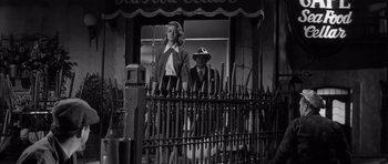 Movie still from “The Tarnished Angels” (1957), directed by Douglas Sirk – A man and a woman standing in front of a fence; Medium shot, Low angle