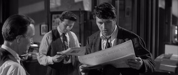 Movie still from “The Tarnished Angels” (1957), directed by Douglas Sirk – Two men in suits and ties looking at a newspaper; Close Up shot, Over the shoulder angle