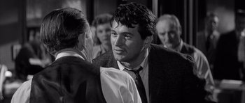 Movie still from “The Tarnished Angels” (1957), directed by Douglas Sirk – A black - and - white photo of a man in a suit and tie; Close Up shot, Over the shoulder angle