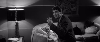 Movie still from “The Tarnished Angels” (1957), directed by Douglas Sirk – A man holding a wine glass next to a baby; Medium shot, High angle