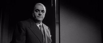 Movie still from “The Tarnished Angels” (1957), directed by Douglas Sirk – An older man wearing a suit and tie; Close Up shot, Low angle