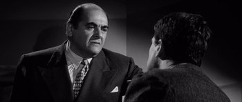 Movie still from “The Tarnished Angels” (1957), directed by Douglas Sirk – An older man wearing a suit talking to a younger man; Close Up shot, Over the shoulder angle