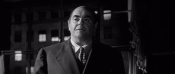 Movie still from “The Tarnished Angels” (1957), directed by Douglas Sirk – Black and white photograph of a man wearing a suit and tie; Close Up shot, Low angle