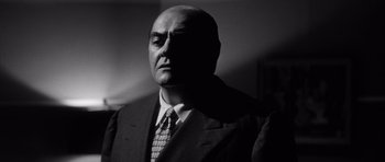 Movie still from “The Tarnished Angels” (1957), directed by Douglas Sirk – Black and white photograph of a man in a suit and tie; Close Up shot, Low angle