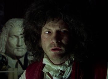 Movie still from “The Tempest” (1979), directed by Derek Jarman – A man in a red vest and white shirt with long black hair; Close Up shot, Low angle