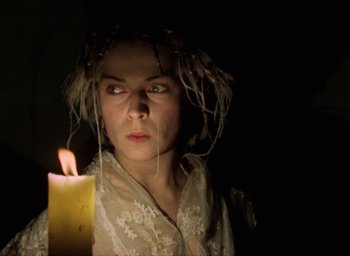 Movie still from “The Tempest” (1979), directed by Derek Jarman – A woman in a white shirt is holding a candle; Close Up shot, High angle