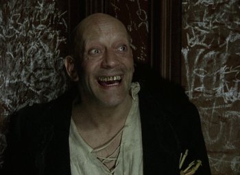 Movie still from “The Tempest” (1979), directed by Derek Jarman – A man with a bald head smiling for the camera; Close Up shot, High angle