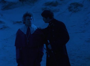 Movie still from “The Tempest” (1979), directed by Derek Jarman – A man and a woman standing next to each other in the dark; Medium shot, Over the shoulder angle