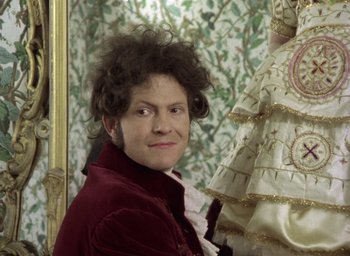 Movie still from “The Tempest” (1979), directed by Derek Jarman – A woman in a red jacket is posing in front of a mirror; Close Up shot, Over the shoulder angle