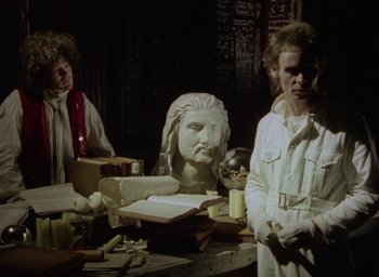 Movie still from “The Tempest” (1979), directed by Derek Jarman – A couple of people that are sitting at a table; Medium shot, Low angle
