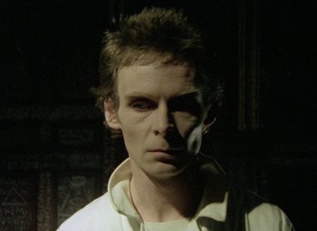 Movie still from “The Tempest” (1979), directed by Derek Jarman – A man in a white shirt is looking at the camera; Close Up shot, Low angle