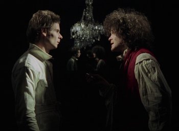 Movie still from “The Tempest” (1979), directed by Derek Jarman – Two men are talking in a dark room; Medium shot, Over the shoulder angle