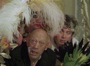 Movie still from “The Tempest” (1979), directed by Derek Jarman – A group of people wearing fancy hats and costumes; Close Up shot, High angle
