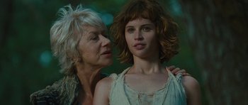 Movie still from “The Tempest” (2010), directed by Julie Taymor – A woman standing next to another woman in front of trees; Close Up shot, Low angle