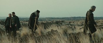 Movie still from “The Tempest” (2010), directed by Julie Taymor – An old man with a hat and a cane walking through a field; Wide shot, Low angle