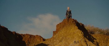 Movie still from “The Tempest” (2010), directed by Julie Taymor – A woman sitting on top of a hill; Wide shot, Low angle