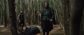 Movie still from “The Tempest” (2010), directed by Julie Taymor – A man dressed as a roman soldier stands in the woods; Wide shot, Low angle