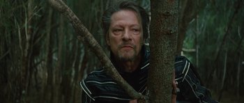 Movie still from “The Tempest” (2010), directed by Julie Taymor – A person holding a stick in a forest; Close Up shot, Low angle