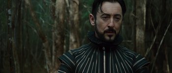 Movie still from “The Tempest” (2010), directed by Julie Taymor – A person wearing a costume near a forest; Close Up shot, Low angle