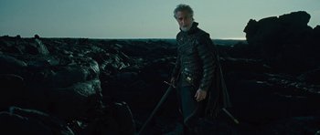 Movie still from “The Tempest” (2010), directed by Julie Taymor – An older man with a sword standing on top of a hill; Medium shot, Low angle