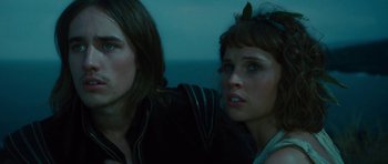 Movie still from “The Tempest” (2010), directed by Julie Taymor – A man and a woman sitting next to each other in front of a body of water; Close Up shot, Low angle