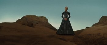 Movie still from “The Tempest” (2010), directed by Julie Taymor – A woman standing on top of a hill in a dress; Wide shot, Low angle