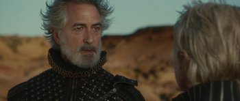 Movie still from “The Tempest” (2010), directed by Julie Taymor – A person with a beard wearing armor; Close Up shot, Over the shoulder angle