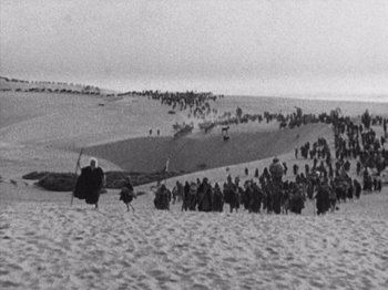 Movie still from “The Ten Commandments” (1923), directed by Cecil B. DeMille – A large group of people gathered in the desert; Extreme Wide shot, High angle