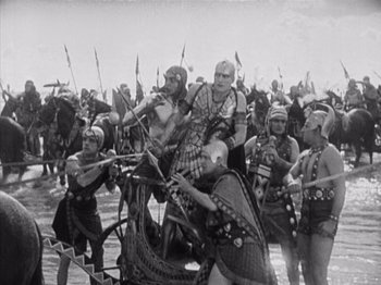 Movie still from “The Ten Commandments” (1923), directed by Cecil B. DeMille – A black and white photo of a group of men on horses; Extreme Wide shot, High angle