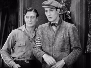 Movie still from “The Ten Commandments” (1923), directed by Cecil B. DeMille – Two men standing next to each other in front of a wall; Medium shot, High angle