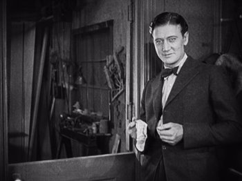 Movie still from “The Ten Commandments” (1923), directed by Cecil B. DeMille – A black and white photo of a man in a suit and bow tie; Medium shot, Low angle