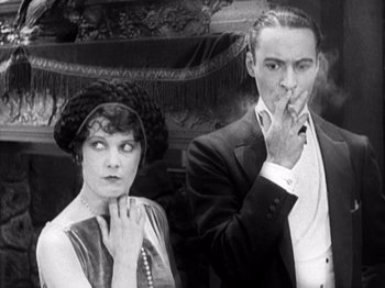 Movie still from “The Ten Commandments” (1923), directed by Cecil B. DeMille – A man and a woman standing next to each other smoking; Medium shot, High angle