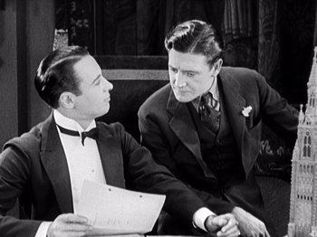 Movie still from “The Ten Commandments” (1923), directed by Cecil B. DeMille – Two men are sitting at a table and one of the men is holding a paper; Medium shot, Over the shoulder angle