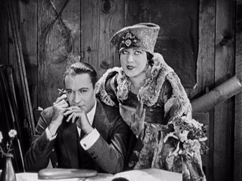 Movie still from “The Ten Commandments” (1923), directed by Cecil B. DeMille – A man and a woman sitting next to each other at a table; Medium shot, Low angle