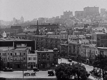 Movie still from “The Ten Commandments” (1923), directed by Cecil B. DeMille – A black and white photo of a city with cars parked on the side of the road; Extreme Wide shot, High angle