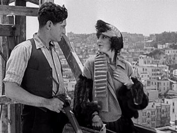 Movie still from “The Ten Commandments” (1923), directed by Cecil B. DeMille – A man and a woman standing next to each other on a building; Medium shot, Low angle