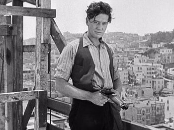 Movie still from “The Ten Commandments” (1923), directed by Cecil B. DeMille – A man standing on top of a building holding a gun; Medium shot, Low angle