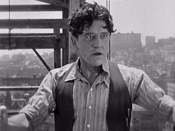 Movie still from “The Ten Commandments” (1923), directed by Cecil B. DeMille – A man standing on top of a building with his hands on his hips; Close Up shot, Low angle