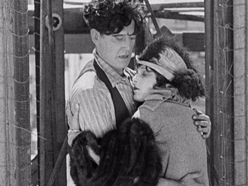 Movie still from “The Ten Commandments” (1923), directed by Cecil B. DeMille – A man and a woman embracing each other in front of an airplane; Medium shot, Over the shoulder angle