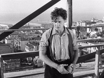 Movie still from “The Ten Commandments” (1923), directed by Cecil B. DeMille – A man standing on top of a building holding a camera; Medium shot, Low angle
