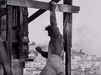 Movie still from “The Ten Commandments” (1923), directed by Cecil B. DeMille – A man hanging from a wooden beam on top of a building; Medium shot, Low angle