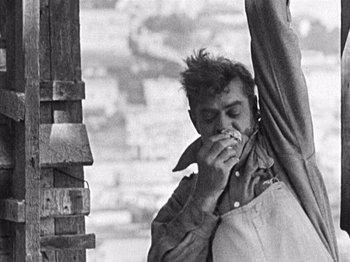 Movie still from “The Ten Commandments” (1923), directed by Cecil B. DeMille – A man in an overalls is eating a piece of food; Medium shot, Low angle