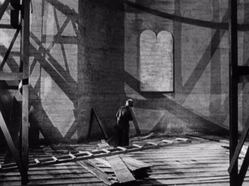 Movie still from “The Ten Commandments” (1923), directed by Cecil B. DeMille – An old photo of a man standing in a building; Wide shot, Low angle
