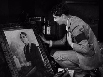 Movie still from “The Ten Commandments” (1923), directed by Cecil B. DeMille – A man is sitting in front of an old picture; Medium shot, Over the shoulder angle