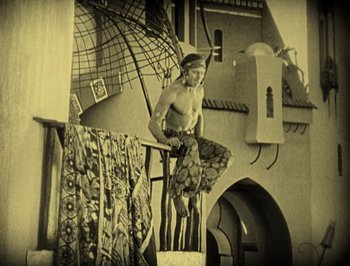Movie still from “The Thief of Bagdad” (1924), directed by Raoul Walsh – A man sitting on a porch with an umbrella; Wide shot, Low angle