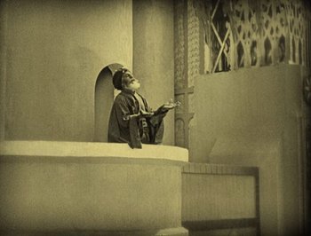 Movie still from “The Thief of Bagdad” (1924), directed by Raoul Walsh – An old photo of a man reading a book; Wide shot, Low angle