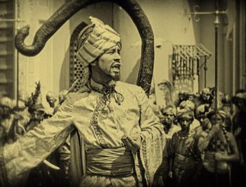 Movie still from “The Thief of Bagdad” (1924), directed by Raoul Walsh – A man in a turban is holding an animal in his hand; Medium shot, High angle