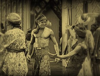 Movie still from “The Thief of Bagdad” (1924), directed by Raoul Walsh – A group of men and women standing next to each other on a stage; Wide shot, High angle