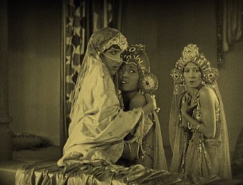 Movie still from “The Thief of Bagdad” (1924), directed by Raoul Walsh – A man and two women dressed in traditional indian garb; Medium shot, High angle